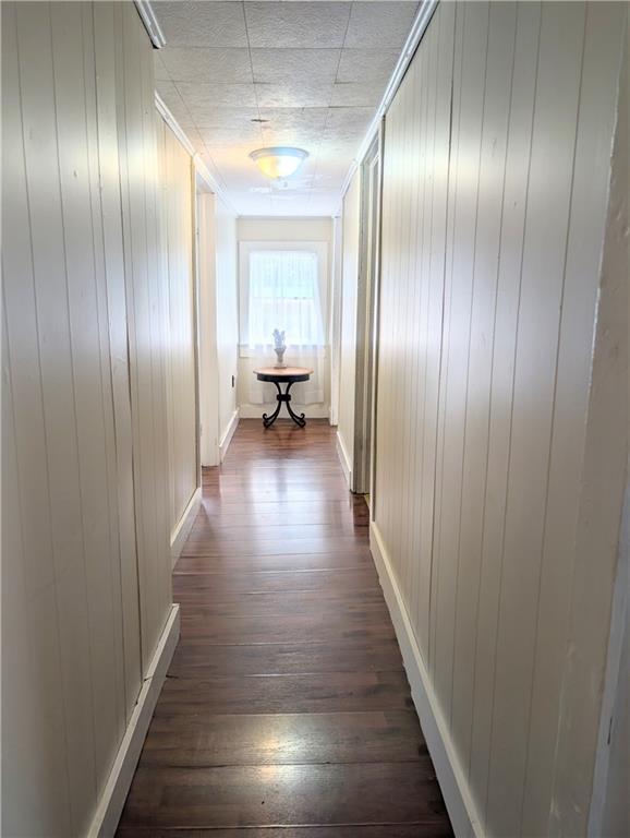 712 N Jefferson Ave, Iola, KS 66749 - corridor with dark wood-style floors and wood walls