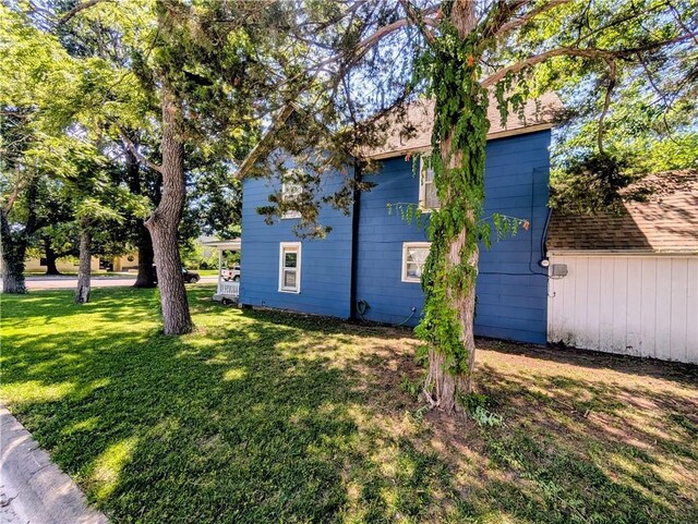 712 N Jefferson Ave, Iola, KS 66749 - view of side of home featuring a yard, an attached garage, and a shingled roof