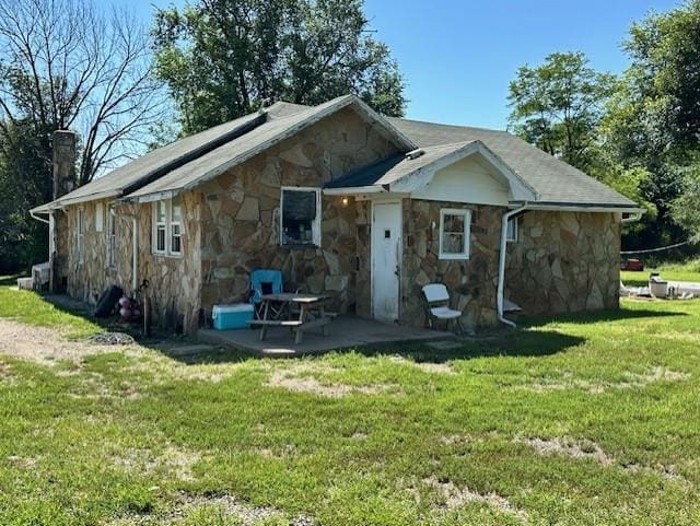 12074 S 1600th Rd, Nevada, MO 64772 - rear view of house featuring stone siding, a patio area, and a lawn