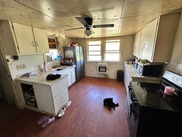 12074 S 1600th Rd, Nevada, MO 64772 - kitchen with appliances with stainless steel finishes, light countertops, a ceiling fan, wood finished floors, and heating unit