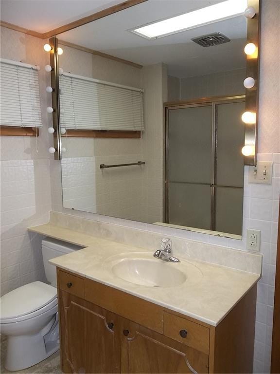 201 S Larson Ave, Chanute, KS 66720 - bathroom featuring tile walls, vanity, and a shower with door