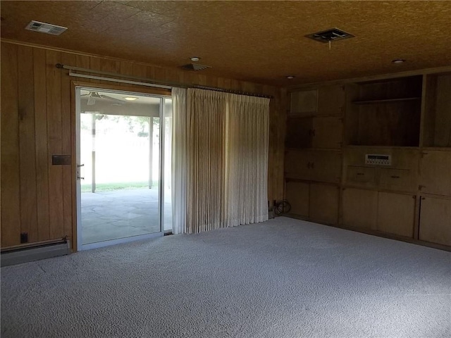 201 S Larson Ave, Chanute, KS 66720 - carpeted spare room featuring wooden walls and a baseboard radiator