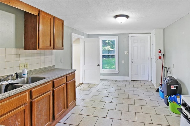 2514 Belmont Ave, Parsons, KS 67357 - kitchen featuring brown cabinets, tasteful backsplash, light countertops, a textured ceiling, and light tile patterned floors
