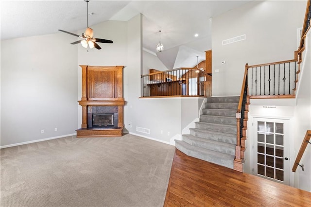 1103 N 2nd St E, Louisburg, KS 66053 - unfurnished living room with ceiling fan, high vaulted ceiling, stairs, a glass covered fireplace, and carpet flooring