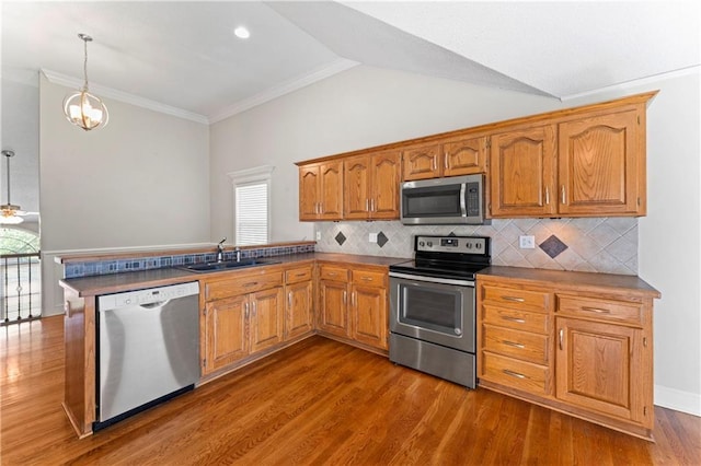 1103 N 2nd St E, Louisburg, KS 66053 - kitchen featuring stainless steel appliances, pendant lighting, brown cabinetry, ornamental molding, and vaulted ceiling