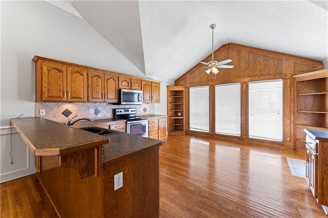 1103 N 2nd St E, Louisburg, KS 66053 - kitchen with appliances with stainless steel finishes, vaulted ceiling, brown cabinets, ceiling fan, and wood finished floors