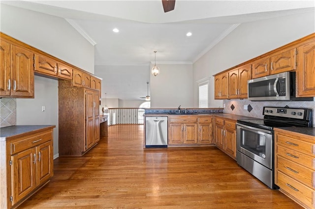 1103 N 2nd St E, Louisburg, KS 66053 - kitchen featuring appliances with stainless steel finishes, crown molding, dark countertops, brown cabinetry, and a peninsula