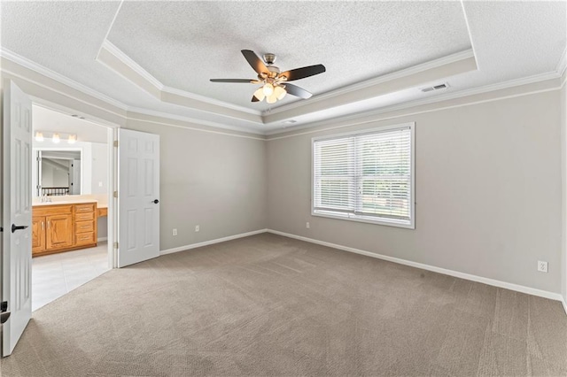 1103 N 2nd St E, Louisburg, KS 66053 - unfurnished bedroom featuring a tray ceiling, ornamental molding, light carpet, a textured ceiling, and connected bathroom