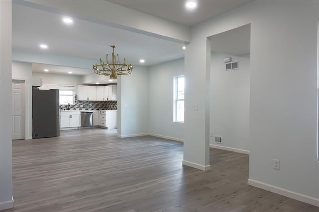 5032 E 8th St, Kansas City, MO 64124 - unfurnished living room with a chandelier, wood finished floors, and recessed lighting