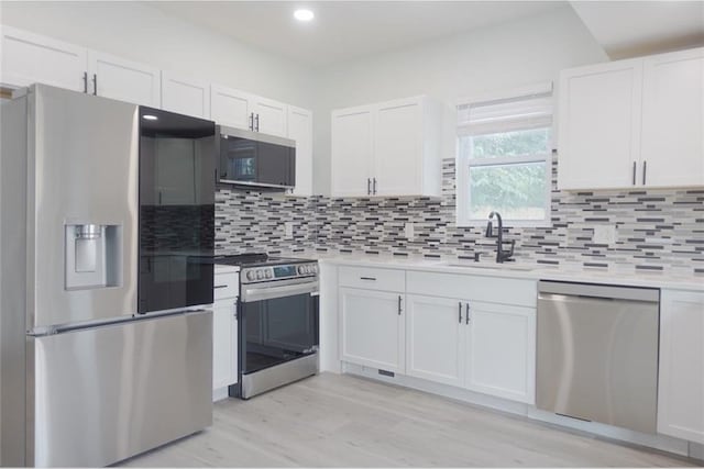 5032 E 8th St, Kansas City, MO 64124 - kitchen featuring stainless steel appliances, white cabinets, light countertops, backsplash, and light wood-type flooring