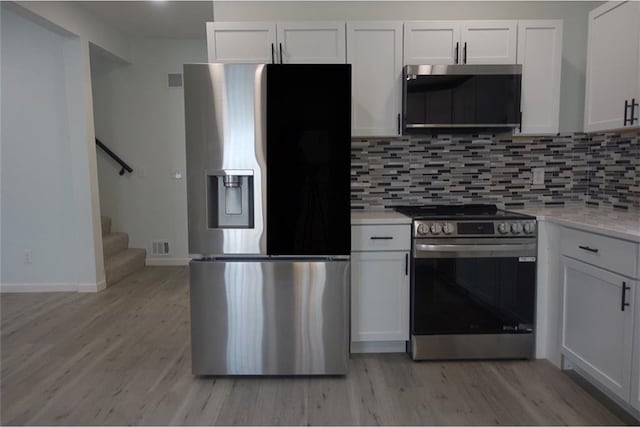 5032 E 8th St, Kansas City, MO 64124 - kitchen with stainless steel appliances, exhaust hood, light countertops, white cabinets, and tasteful backsplash