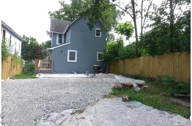 5032 E 8th St, Kansas City, MO 64124 - rear view of house featuring a fenced backyard, a shingled roof, and a deck