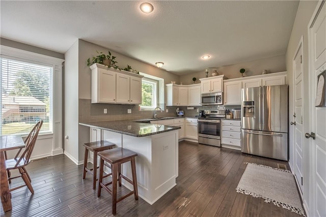 23317 W 52nd Ter, Shawnee, KS 66226 - kitchen with appliances with stainless steel finishes, white cabinets, a peninsula, dark wood-type flooring, and recessed lighting