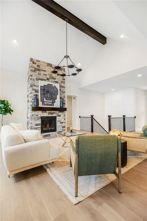 16567 W 170th St, Olathe, KS 66062 - living room with beamed ceiling, wood finished floors, high vaulted ceiling, a stone fireplace, and a chandelier