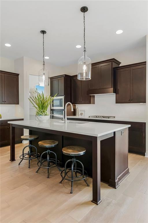 16567 W 170th St, Olathe, KS 66062 - kitchen with appliances with stainless steel finishes, recessed lighting, light countertops, dark brown cabinets, and a kitchen island with sink