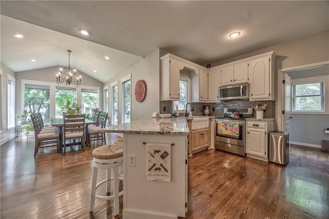 11508 Hauser St, Overland Park, KS 66210 - kitchen featuring stainless steel appliances, a peninsula, lofted ceiling, light stone countertops, and a chandelier
