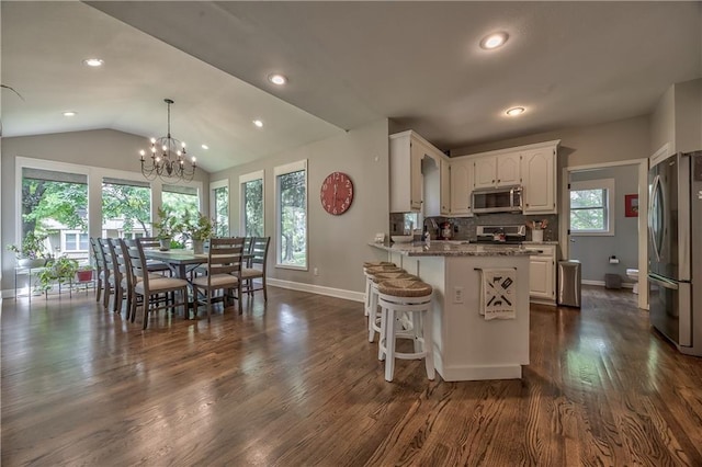 11508 Hauser St, Overland Park, KS 66210 - kitchen with appliances with stainless steel finishes, white cabinetry, a peninsula, a chandelier, and a breakfast bar area
