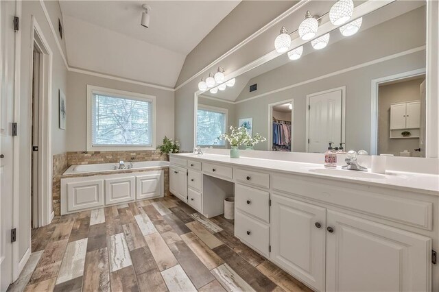 11508 Hauser St, Overland Park, KS 66210 - bathroom featuring lofted ceiling, double vanity, a garden tub, a spacious closet, and wood finished floors