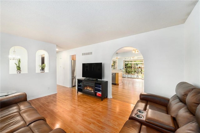 7608 N Serene Ave, Kansas City, MO 64152 - living area with light wood-type flooring, arched walkways, and a textured ceiling