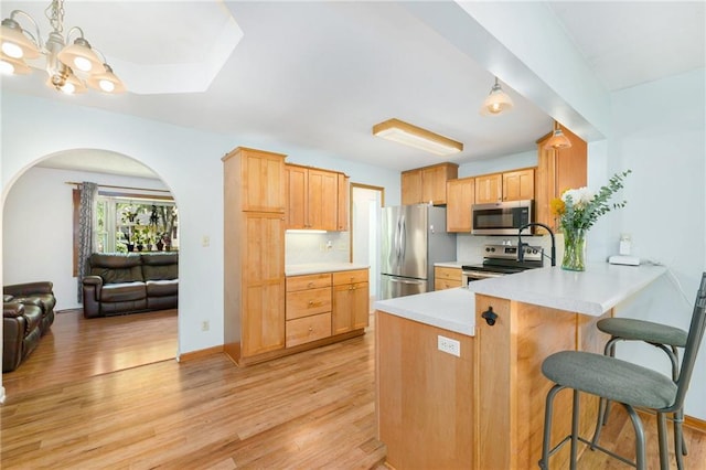 7608 N Serene Ave, Kansas City, MO 64152 - kitchen featuring stainless steel appliances, light wood-type flooring, arched walkways, and light countertops