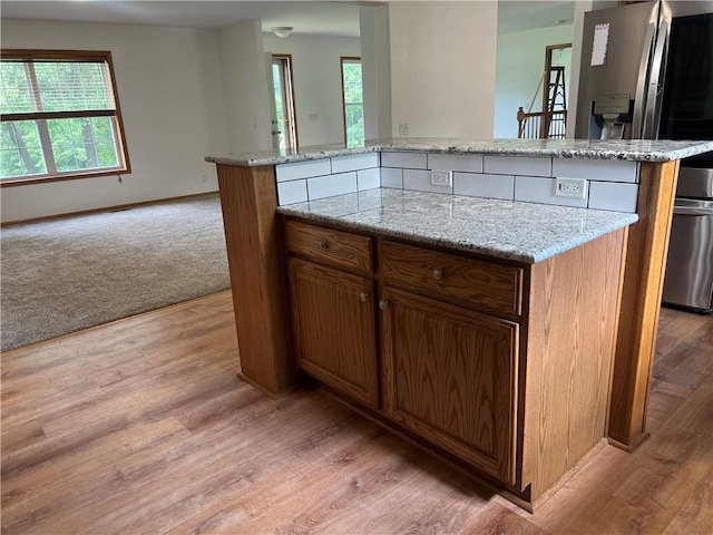 36987 W 63rd St, Camden, MO 64017 - kitchen with light wood-style floors, light stone countertops, brown cabinets, and open floor plan