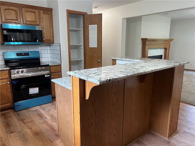 36987 W 63rd St, Camden, MO 64017 - kitchen featuring stainless steel electric stove, light wood-type flooring, a kitchen island, and a kitchen breakfast bar