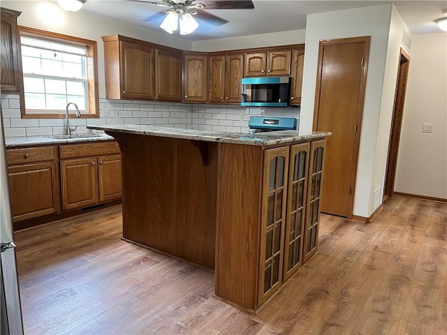 36987 W 63rd St, Camden, MO 64017 - kitchen featuring stainless steel microwave, light wood finished floors, a ceiling fan, and decorative backsplash