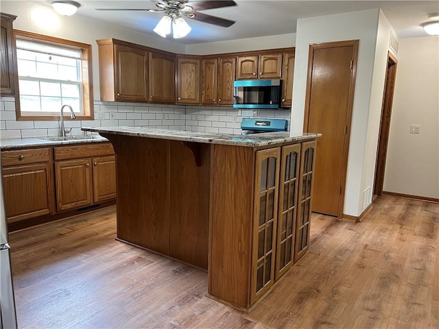 36987 W 63rd St, Camden, MO 64017 - kitchen with stainless steel microwave, ceiling fan, light wood-style floors, and backsplash