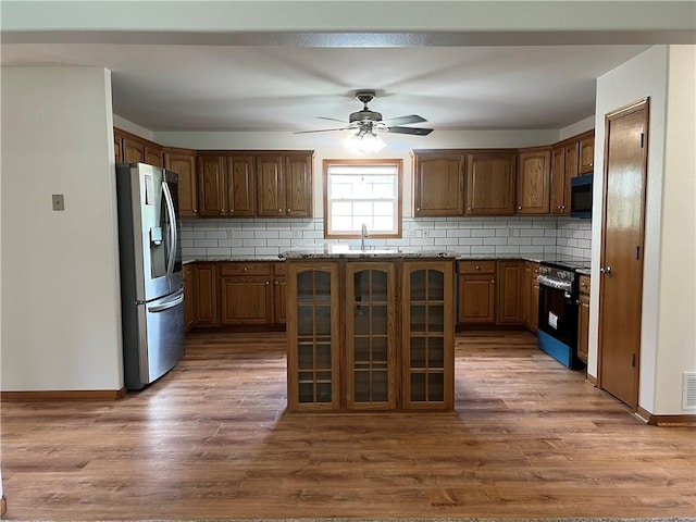 36987 W 63rd St, Camden, MO 64017 - kitchen featuring appliances with stainless steel finishes, a ceiling fan, tasteful backsplash, and wood finished floors