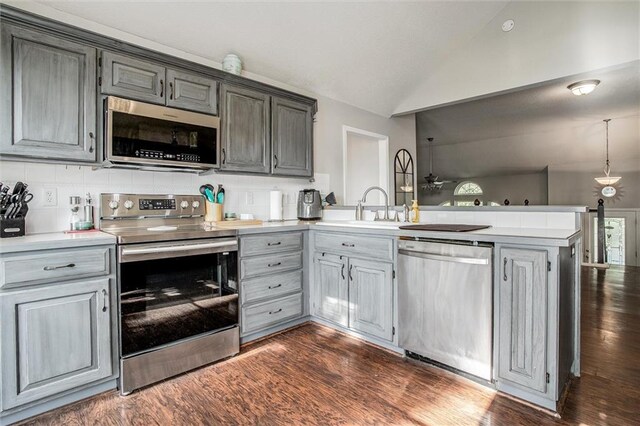 5323 Kenton St, Shawnee, KS 66226 - kitchen featuring appliances with stainless steel finishes, a peninsula, vaulted ceiling, light countertops, and dark wood-style floors