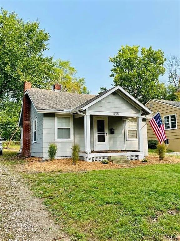 8007 Mercier St, Kansas City, MO 64114 - view of front facade featuring covered porch, a chimney, a front yard, and roof with shingles