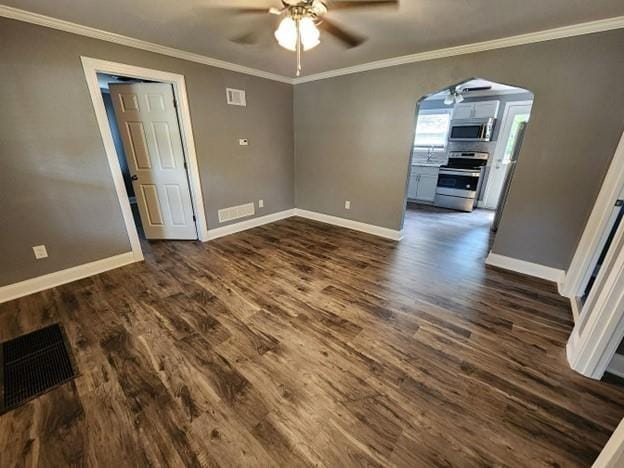 477 Shawnee Rd, Kansas City, KS 66103 - unfurnished room featuring a ceiling fan, dark wood finished floors, arched walkways, and ornamental molding