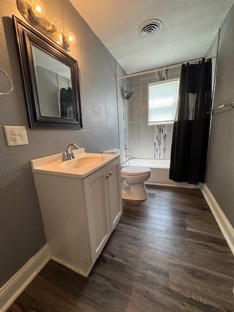 477 Shawnee Rd, Kansas City, KS 66103 - bathroom with vanity, shower / bathtub combination with curtain, wood finished floors, and a textured wall
