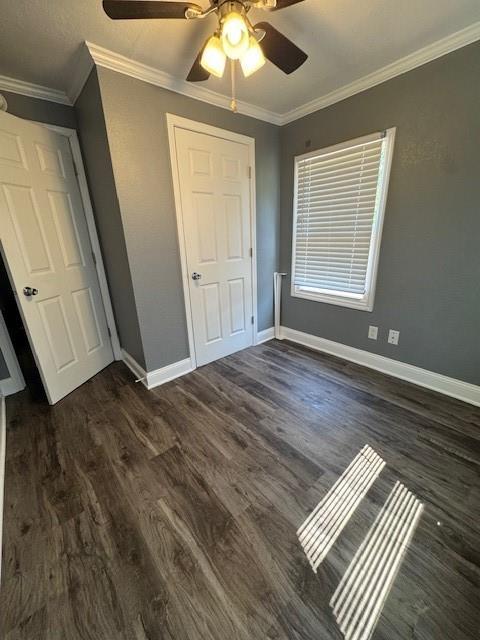 477 Shawnee Rd, Kansas City, KS 66103 - unfurnished bedroom featuring crown molding, dark wood-style flooring, and a ceiling fan