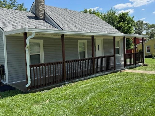 477 Shawnee Rd, Kansas City, KS 66103 - view of front of property with a chimney, a porch, a shingled roof, and a front lawn