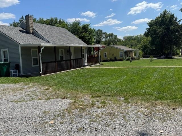 477 Shawnee Rd, Kansas City, KS 66103 - view of home's exterior with a porch, a chimney, a lawn, and roof with shingles