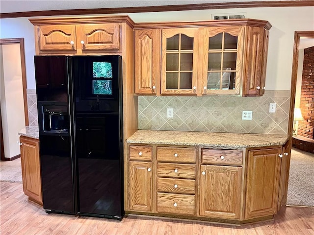 11510 Ridge Dr, Sugar Creek, MO 64054 - kitchen featuring black refrigerator with ice dispenser, glass insert cabinets, light stone countertops, and light wood-style flooring
