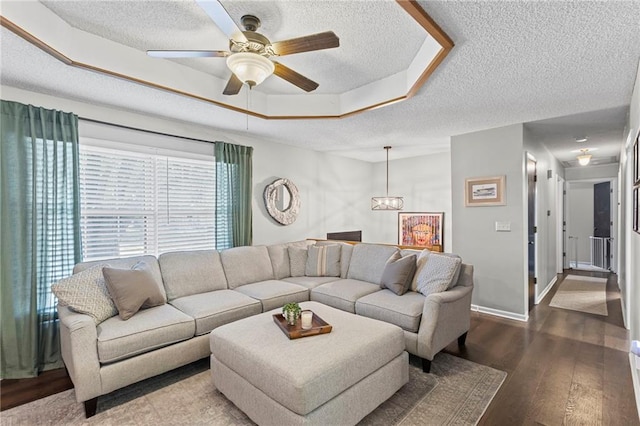 1413 SE 1st Ter, Lees Summit, MO 64063 - living room featuring a textured ceiling, a raised ceiling, a ceiling fan, wood finished floors, and a chandelier