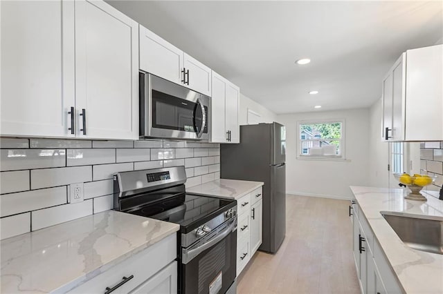 2 Overhill Dr, Paola, KS 66071 - kitchen with appliances with stainless steel finishes, tasteful backsplash, white cabinetry, light wood-style flooring, and recessed lighting