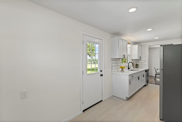 2 Overhill Dr, Paola, KS 66071 - kitchen with freestanding refrigerator, light countertops, light wood finished floors, dishwashing machine, and backsplash