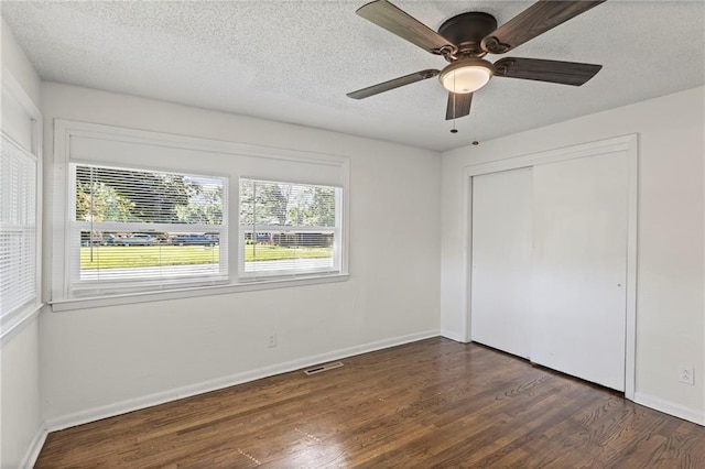 2 Overhill Dr, Paola, KS 66071 - unfurnished bedroom with multiple windows, wood finished floors, a closet, a textured ceiling, and ceiling fan