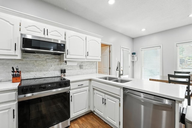 5136 NE Ash Grove Dr, Lees Summit, MO 64064 - kitchen with appliances with stainless steel finishes, a peninsula, decorative backsplash, light countertops, and recessed lighting