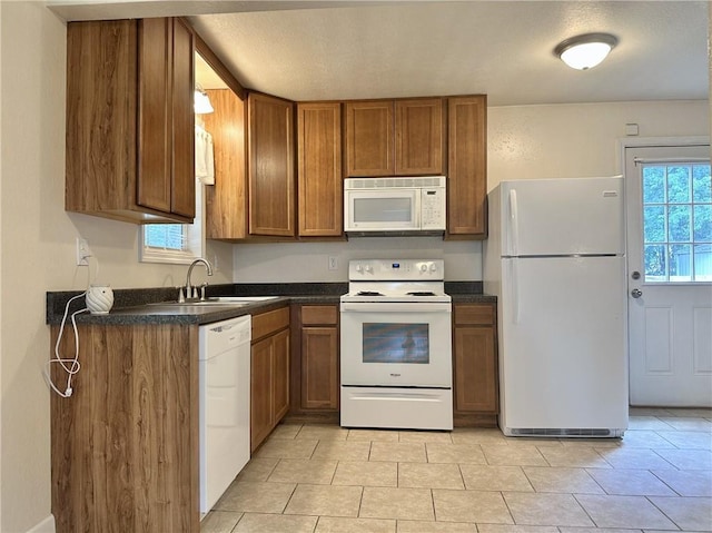400 Webster St, Chillicothe, MO 64601 - kitchen with white appliances, brown cabinetry, dark countertops, light tile patterned flooring, and a textured ceiling