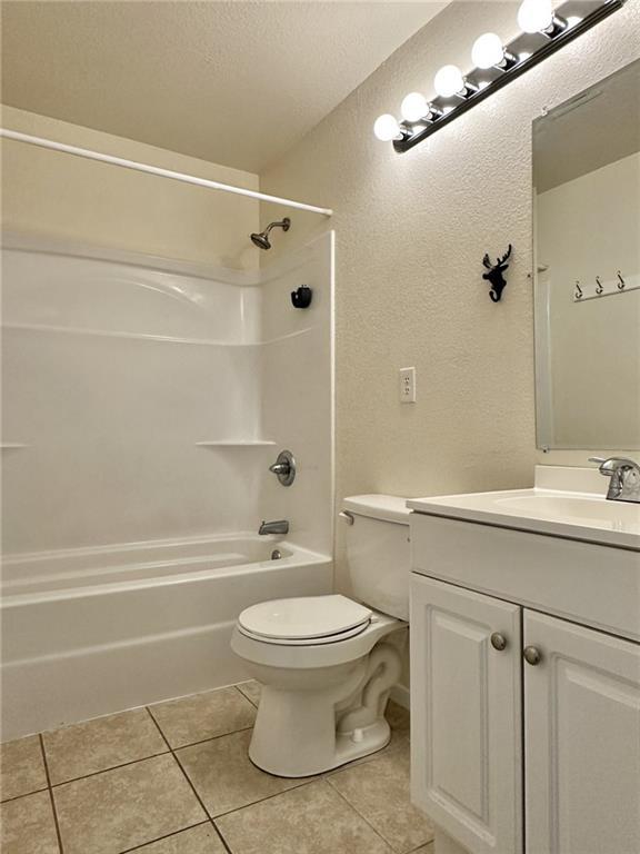 400 Webster St, Chillicothe, MO 64601 - full bathroom featuring a textured wall, tile patterned flooring, vanity, shower / bathtub combination, and a textured ceiling