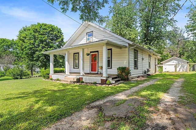 1312 N Main St, Nevada, MO 64772 - view of front of house with a porch, a front yard, an outbuilding, and driveway