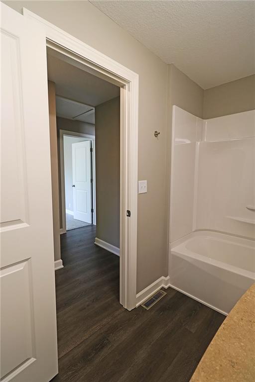901 School Rd, Peculiar, MO 64078 - bathroom featuring wood finished floors, shower / washtub combination, and a textured ceiling