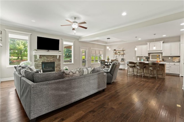 22908 E 41st Ter S, Blue Springs, MO 64015 - living area featuring a stone fireplace, a ceiling fan, dark wood finished floors, recessed lighting, and crown molding