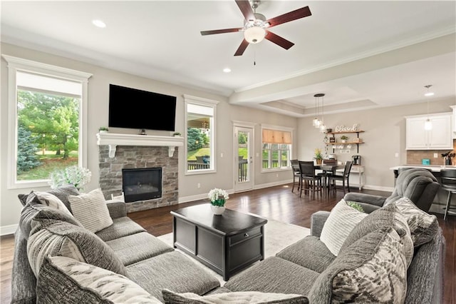 22908 E 41st Ter S, Blue Springs, MO 64015 - living room featuring wood finished floors, ceiling fan, a stone fireplace, crown molding, and a raised ceiling