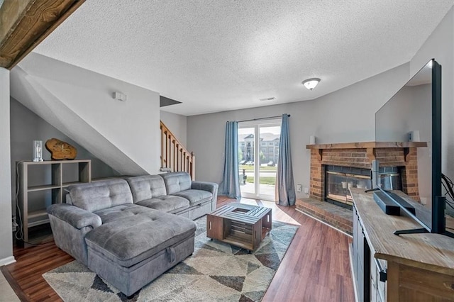 518 NE 6th St Unit A, Blue Springs, MO 64014 - living area with wood finished floors, a brick fireplace, stairs, and a textured ceiling
