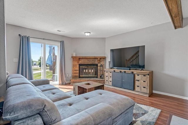 518 NE 6th St Unit A, Blue Springs, MO 64014 - living room with a textured ceiling, wood finished floors, stairs, a brick fireplace, and beam ceiling